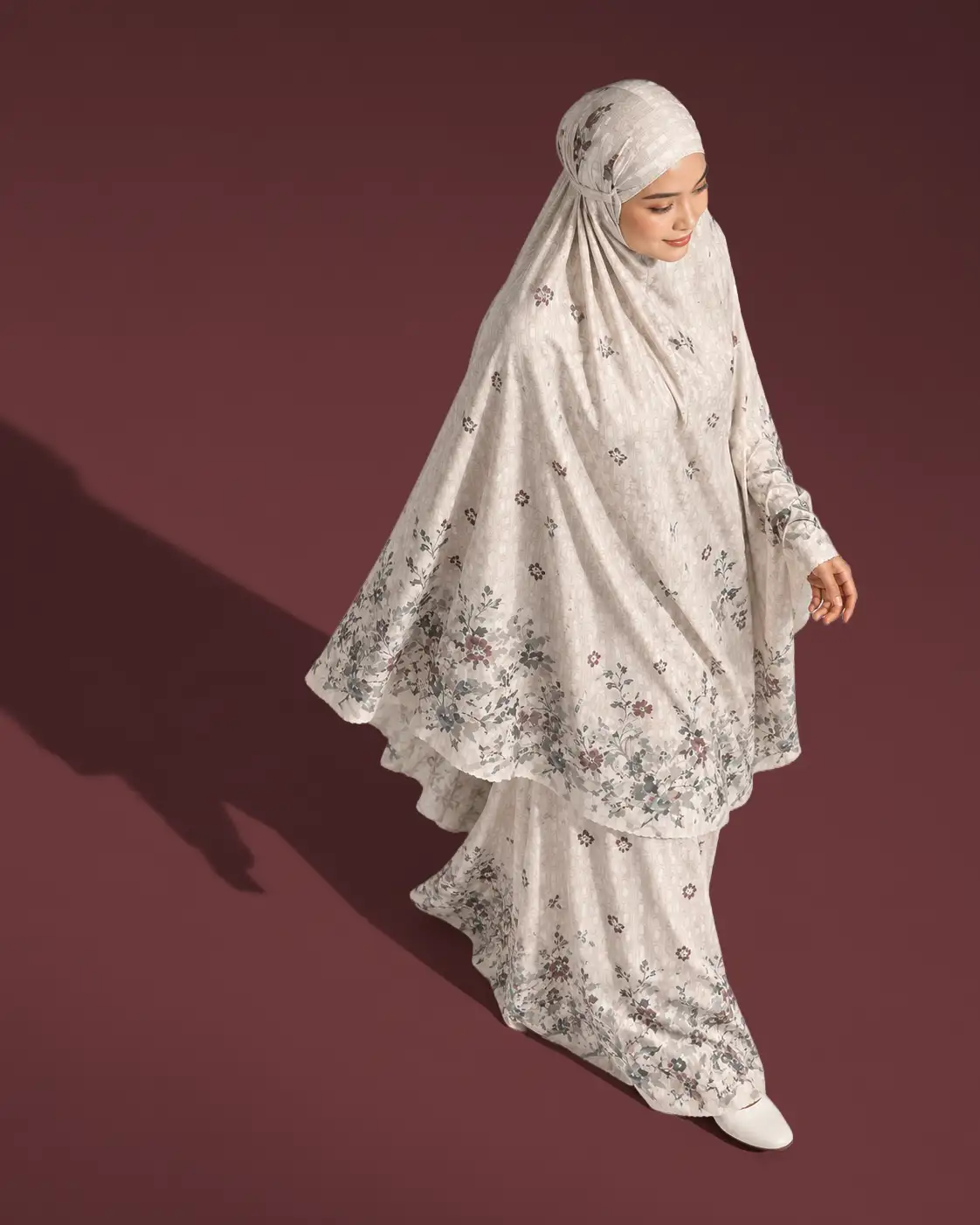 Model mengenakan mukena putih bermotif bunga, koleksi Raya